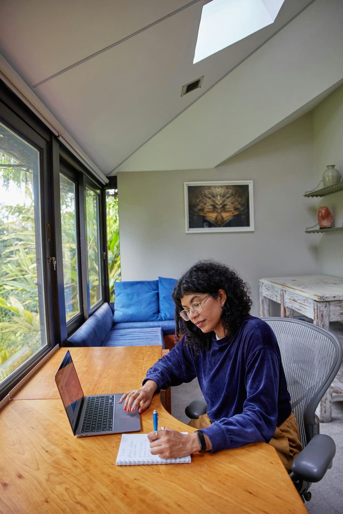 A woman writing notes beside her laptop