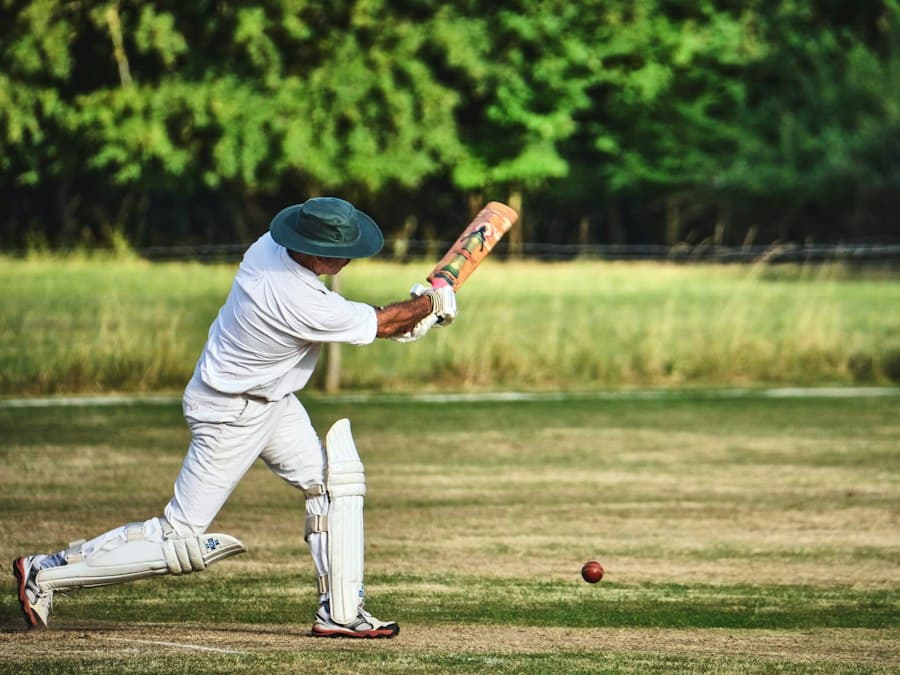 A batter in whites playing a shot on a cricket field