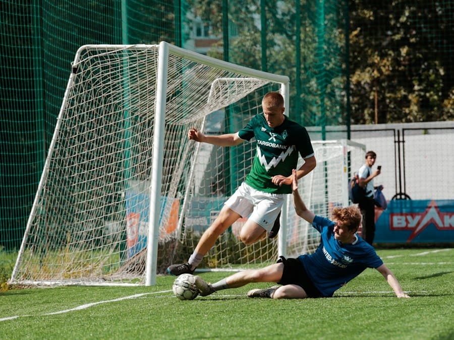 A sliding tackle in front of goal on a grass pitch