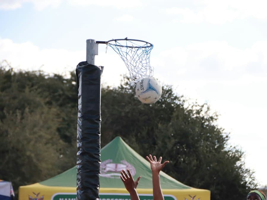 A netball dropping through the hoop